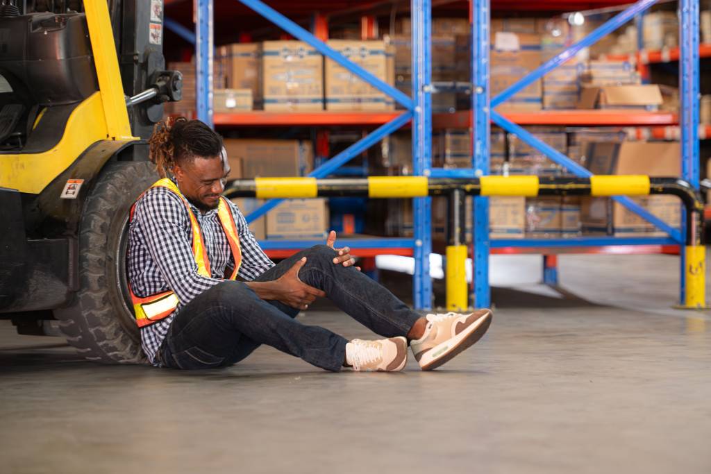 An injured warehouse worker holding his knee.